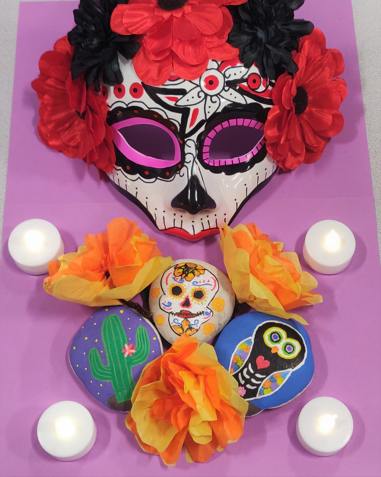 Painted rocks designed with a colorful owl, a cactus, and a sugar skull