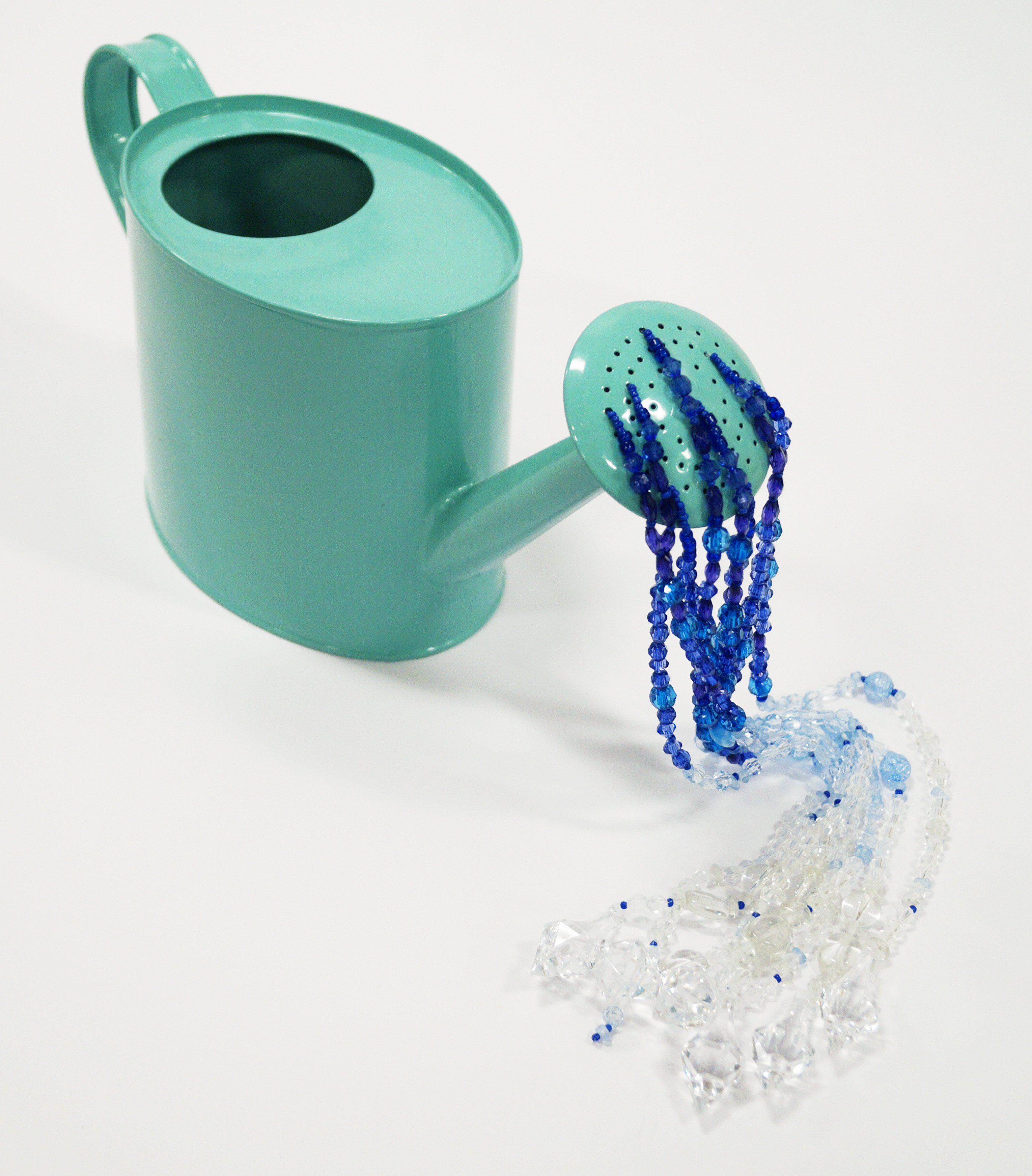 Watering can strung with beads to imitate water.