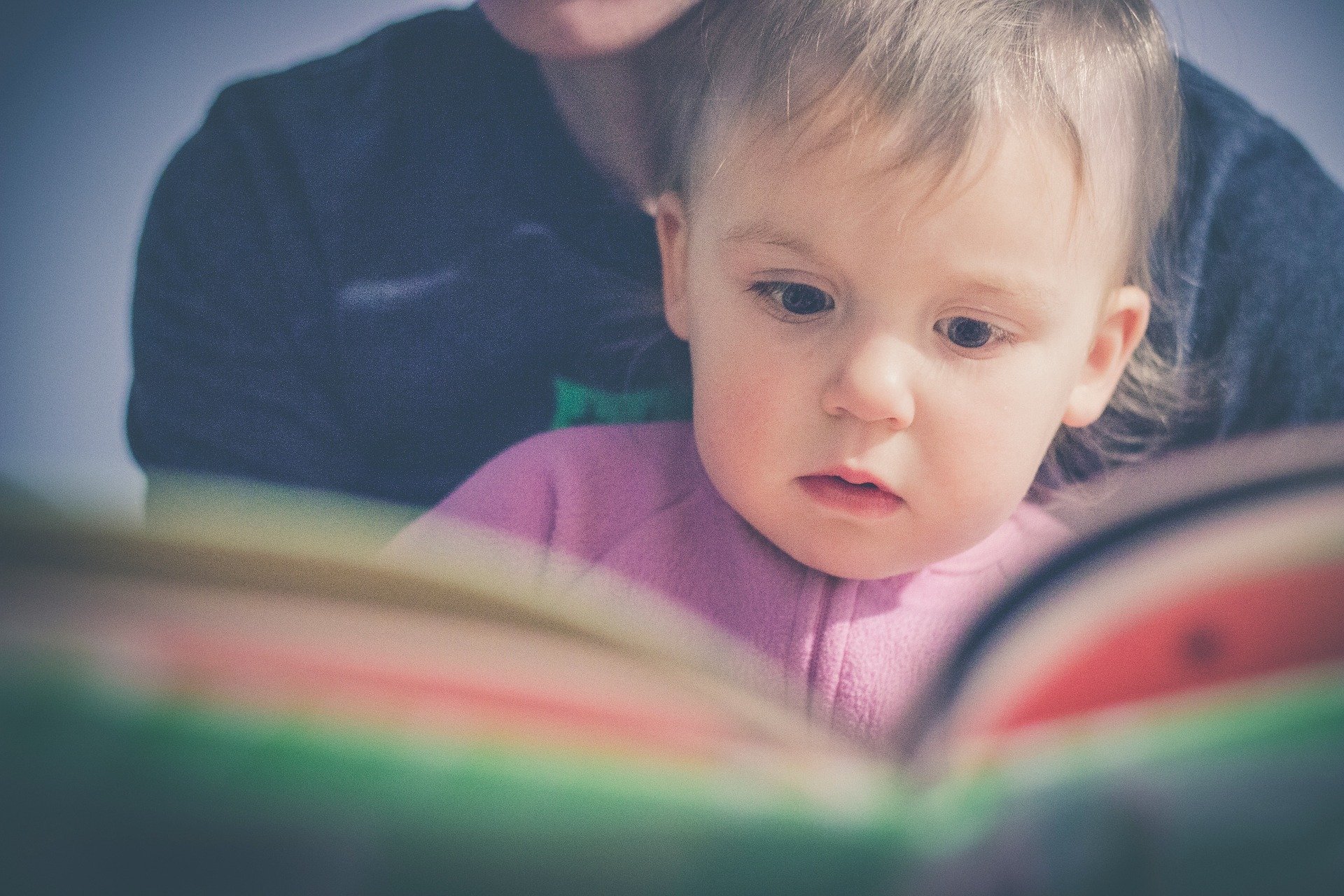 baby on parent's lap reading book