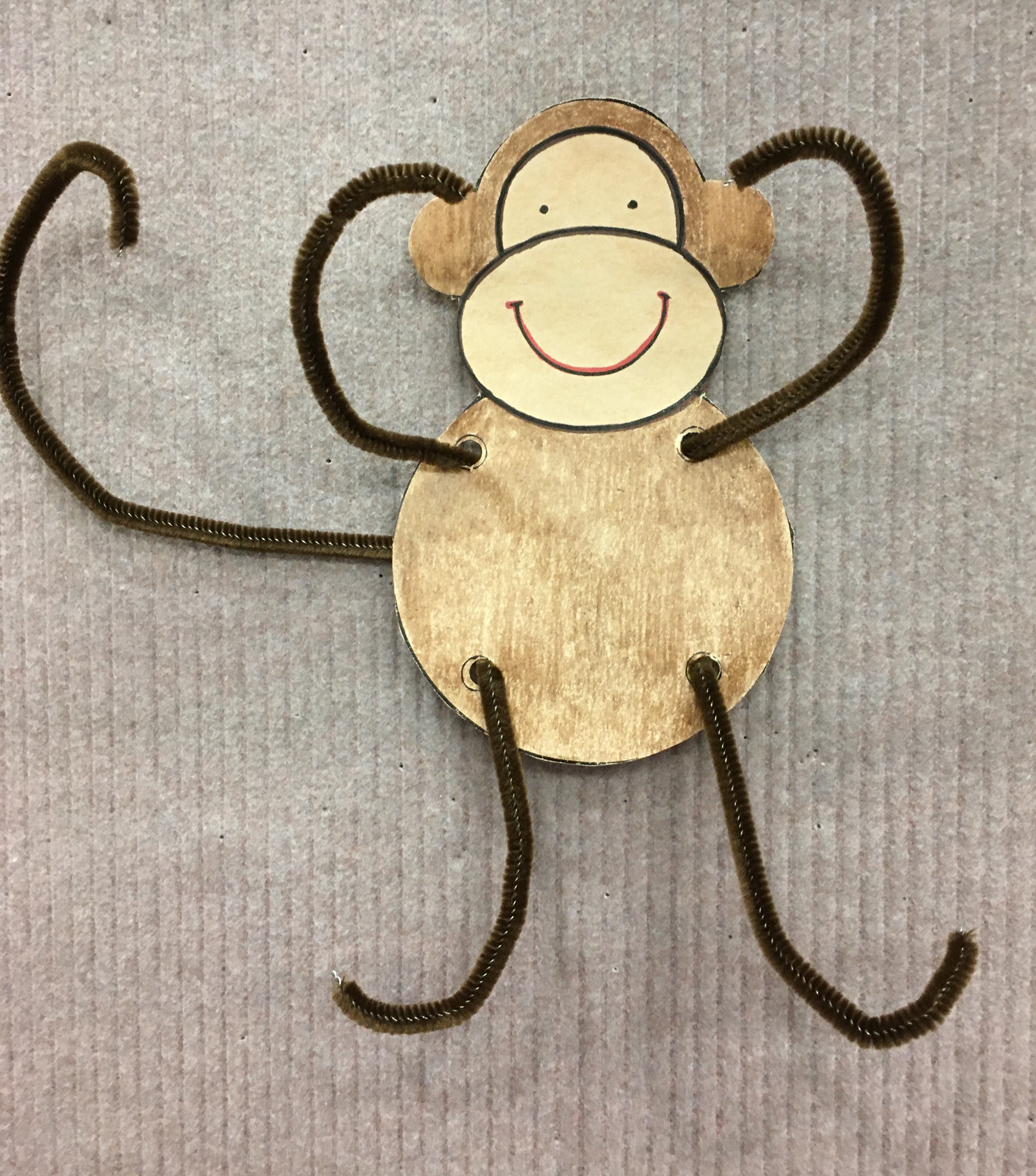 smiling monkey with brown chenille stem arms, legs and tail