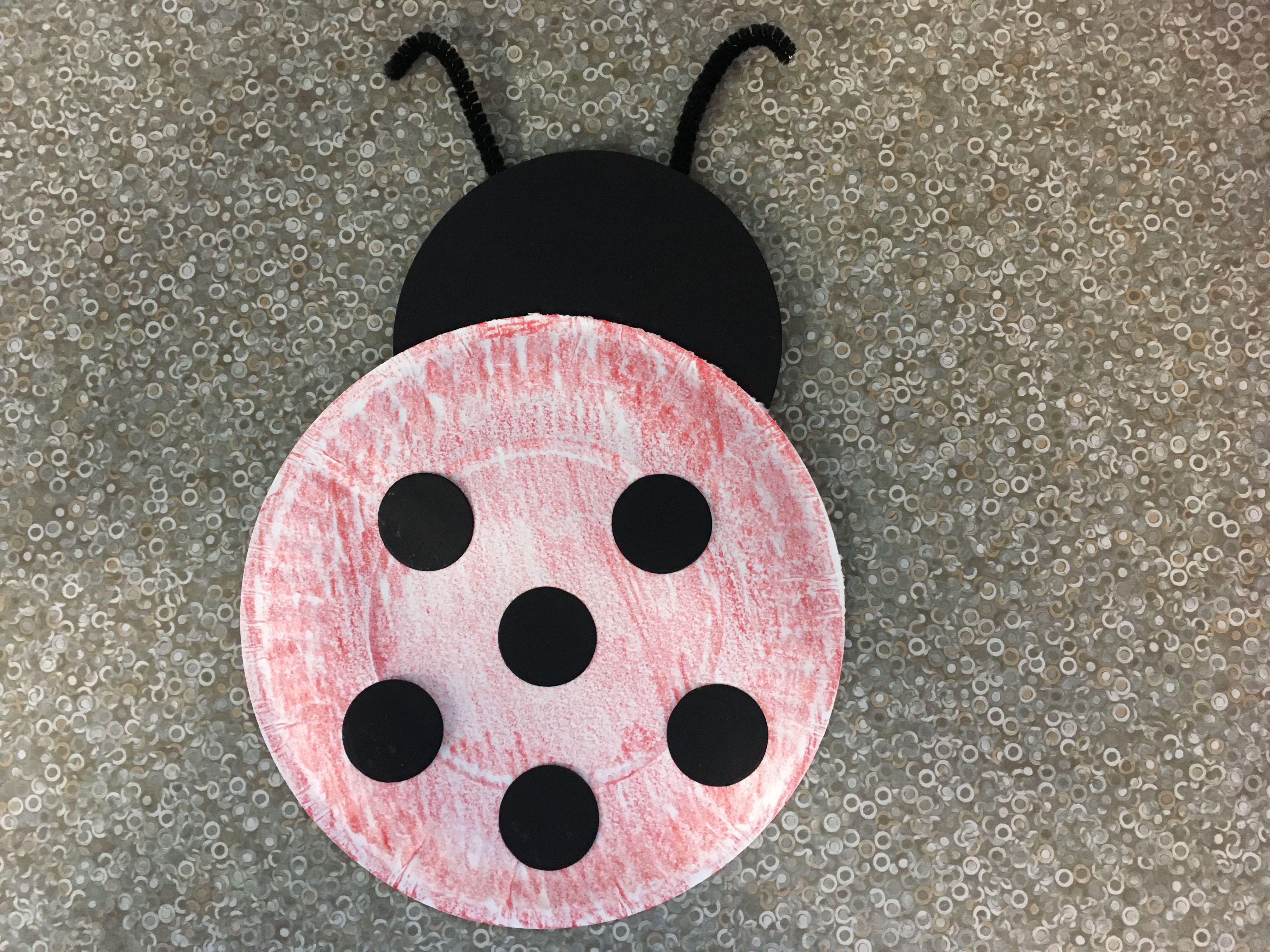 red paper plate lady bug with black spots, black head and black antennae.