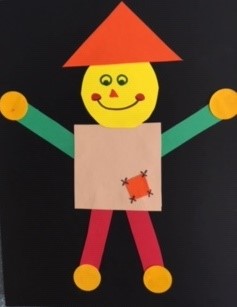 brown square body, yellow circle head , orange triangle hat, green rectangle arms, red rectangle legs, gold circle hands & feet on black rectangle paper