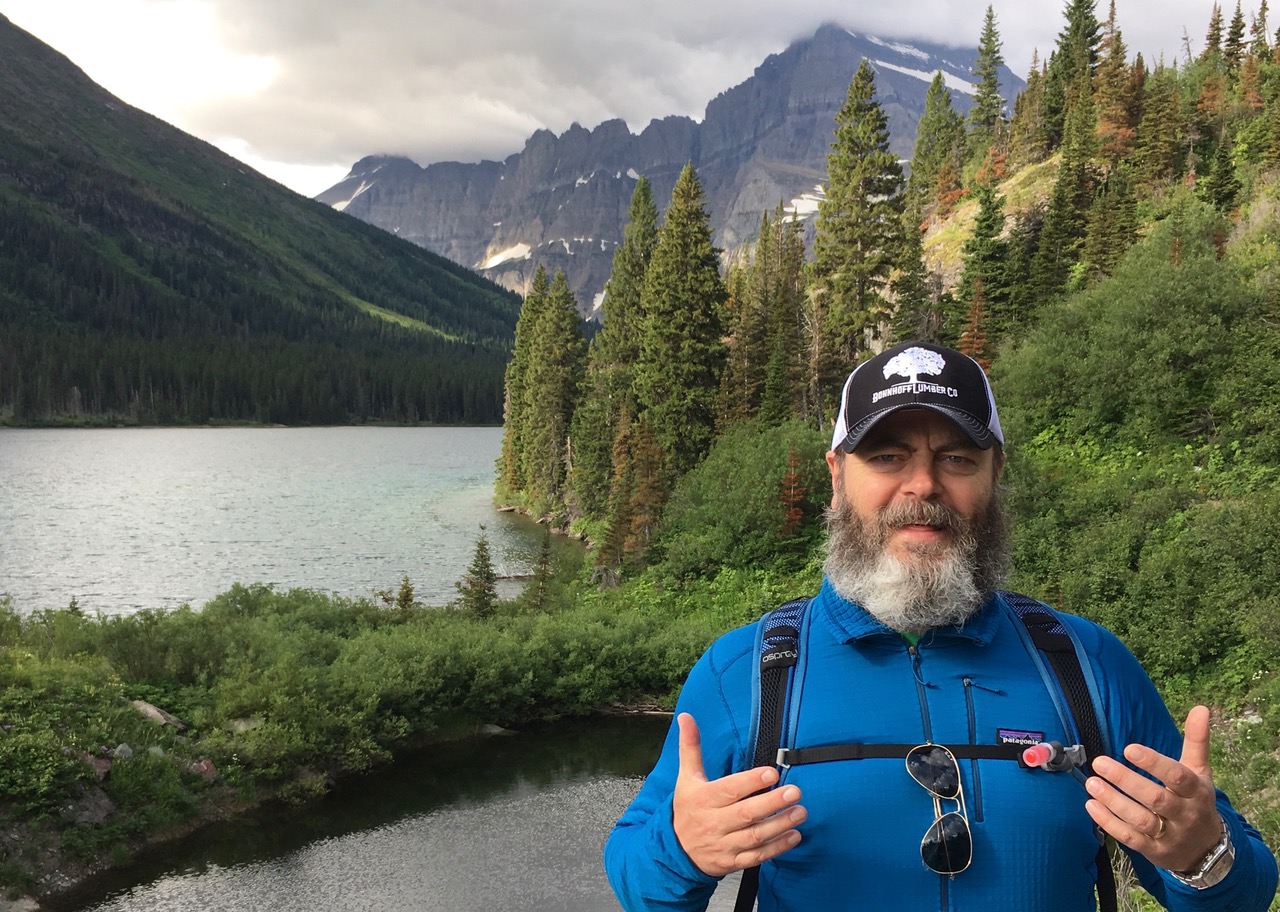 Nick Offerman standing outside in front of a lake and mountain