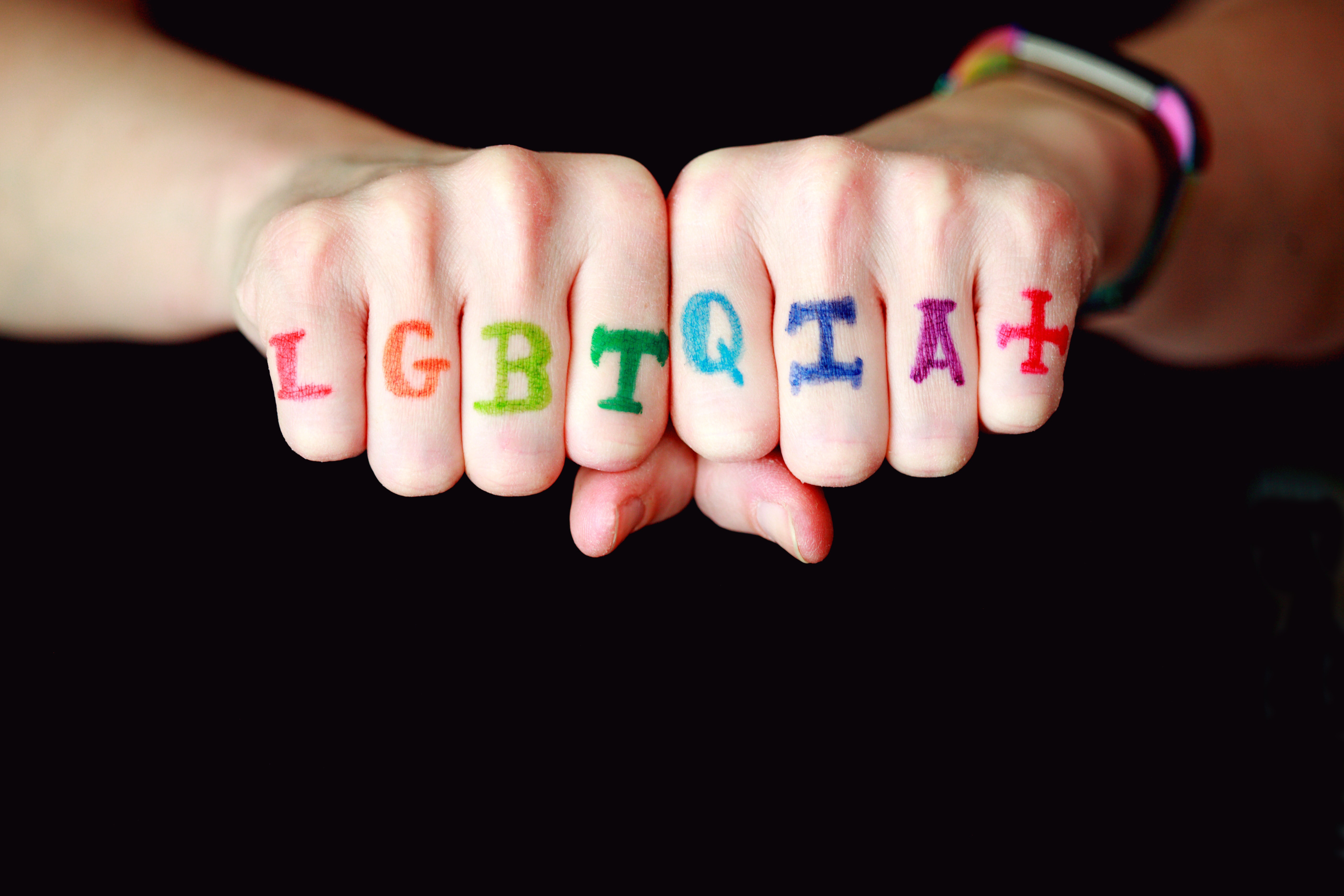 Knuckles of a person displaying the letter LGBTQIA+