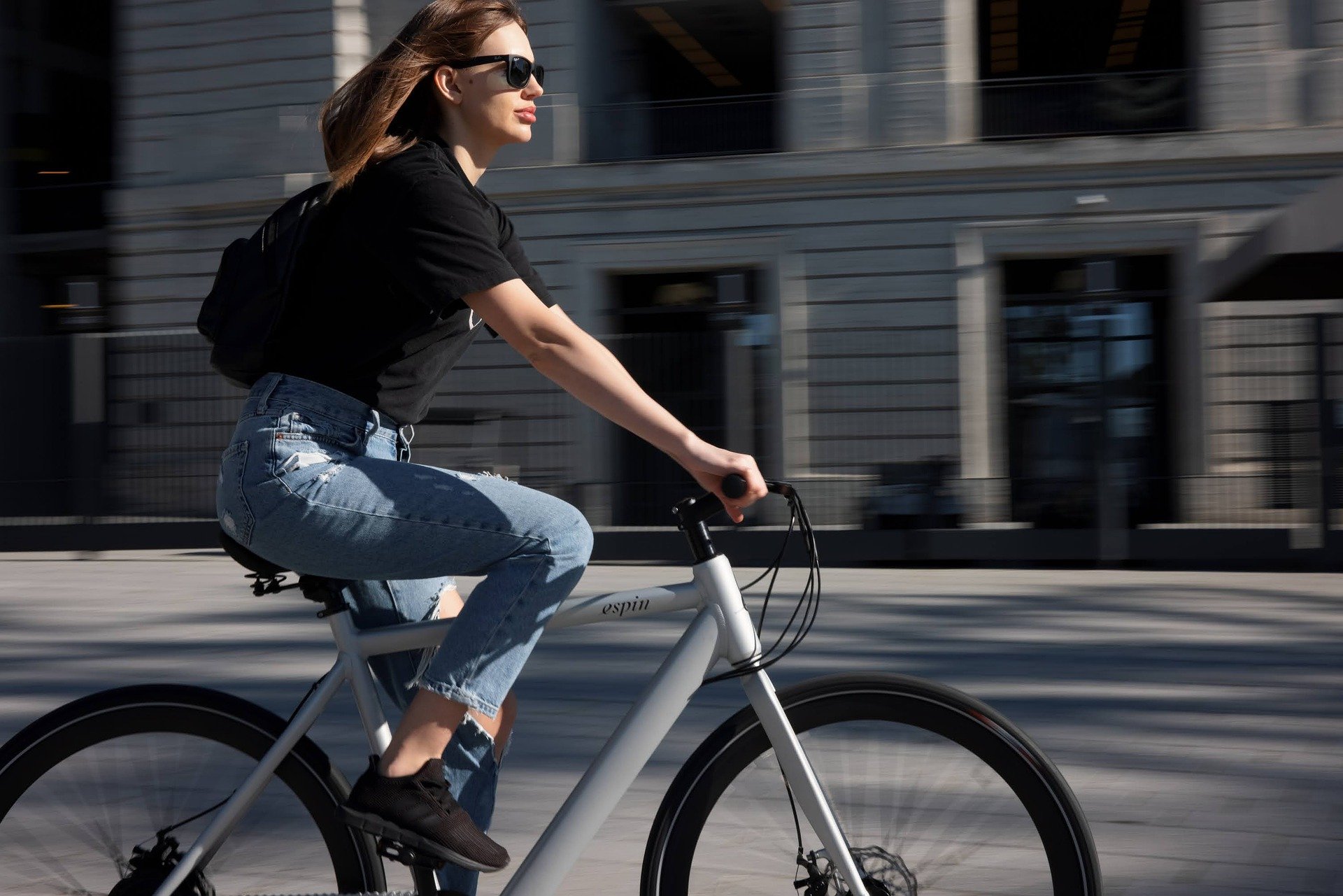 white woman in jeans riding a bike in a city