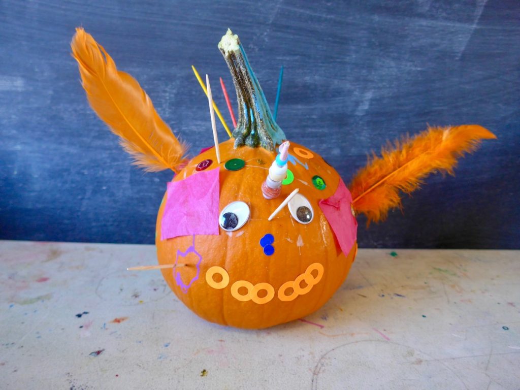 Small pumpkin with feathers and googly eyes