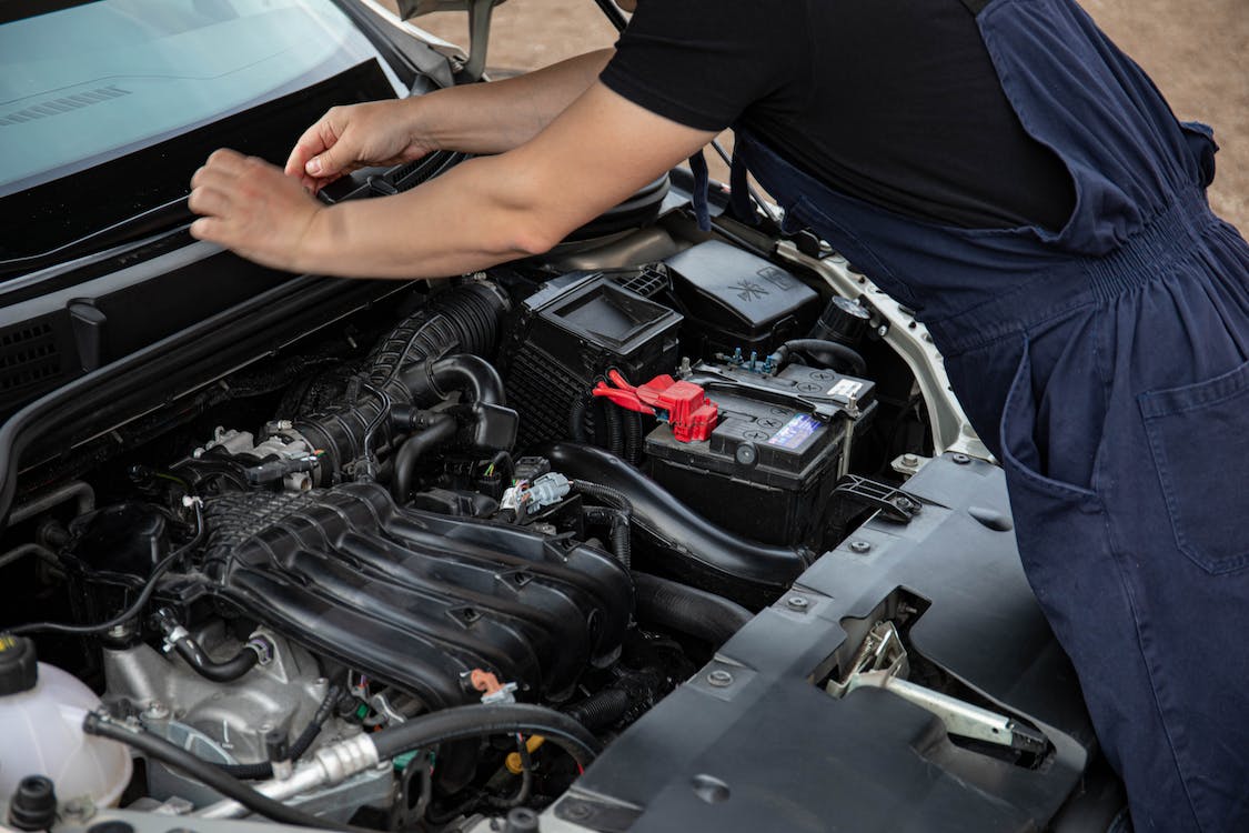 Image of a person working under the hood of a car.