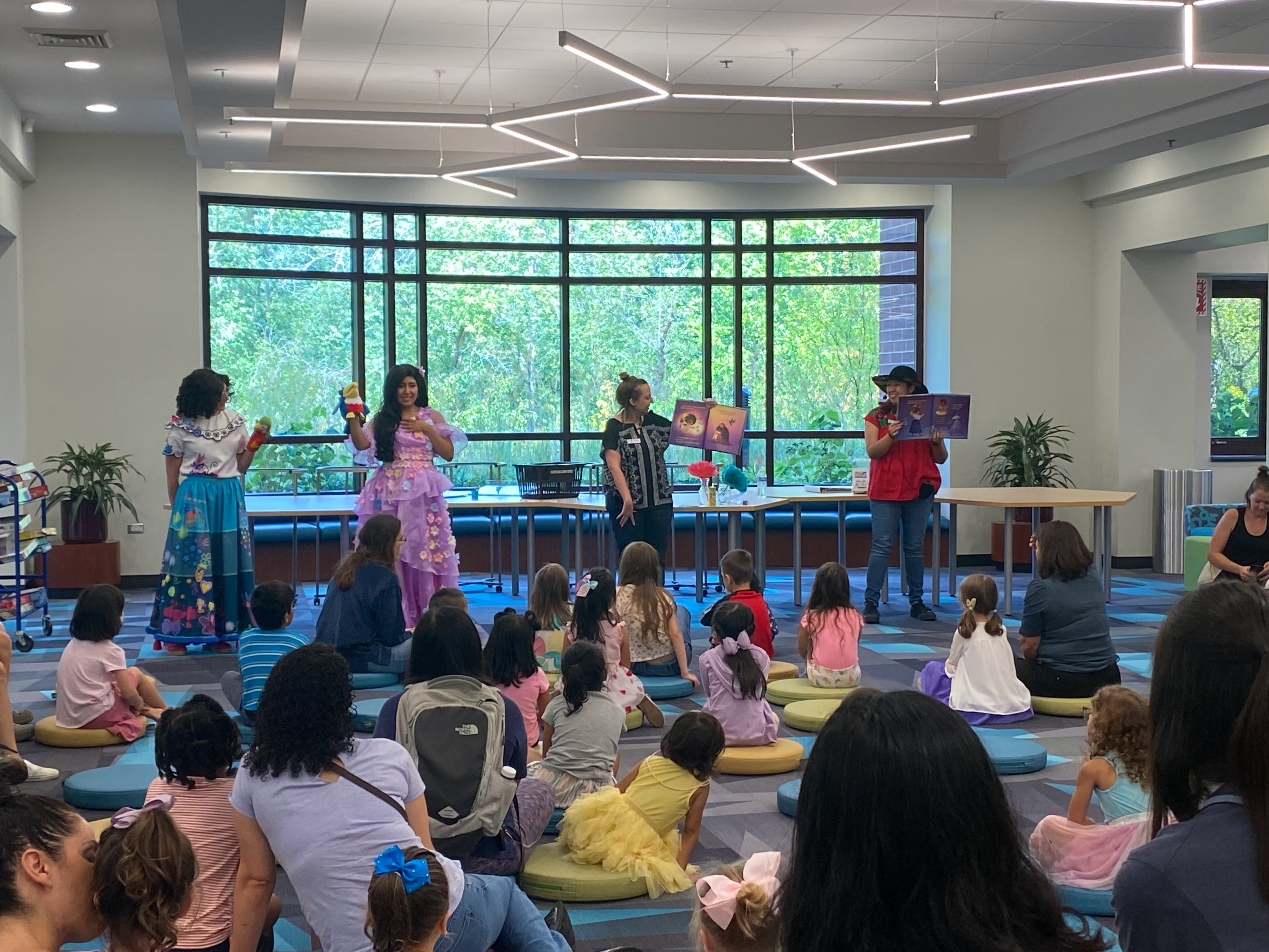 Two Princesses and two library staff reading a story to young members. 