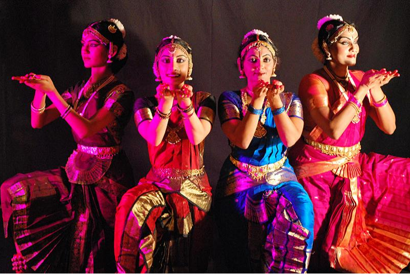 Four dancers from the Mudra Dance Academy posing in traditional Indian clothing.