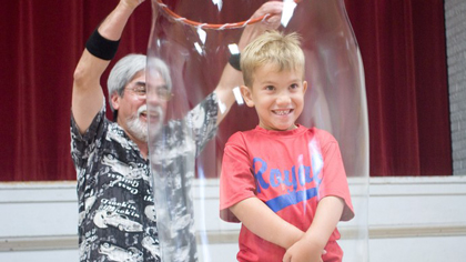 Ben enclosing a smiling child volunteer into a bubble