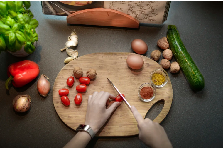Image of hands slicing grape tomatoes on a cutting board.