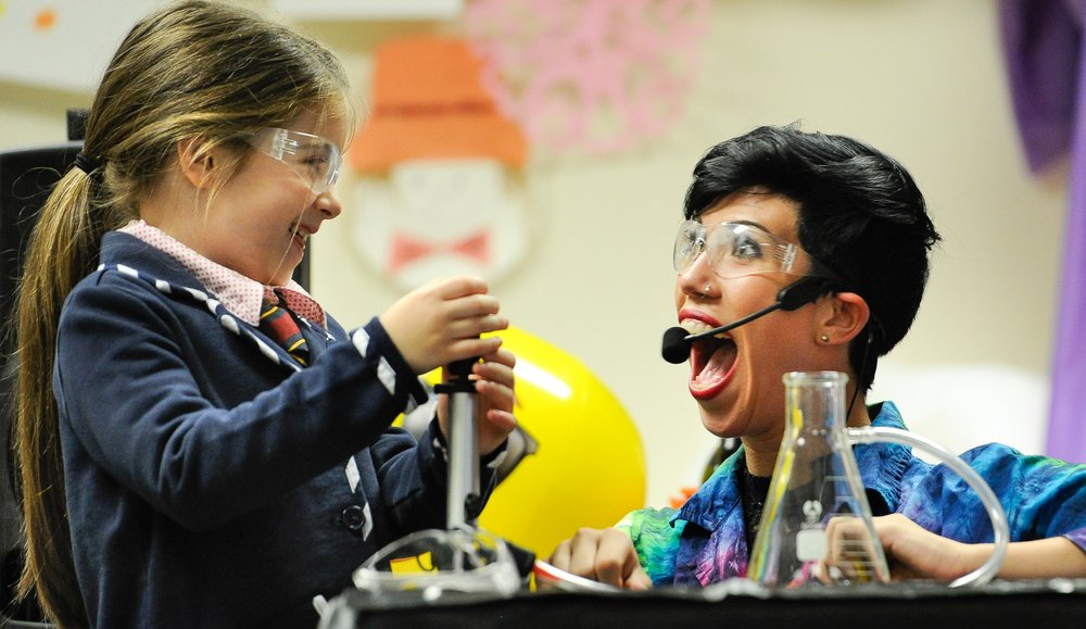 Young girl next to a scientist holding measurement instruments.