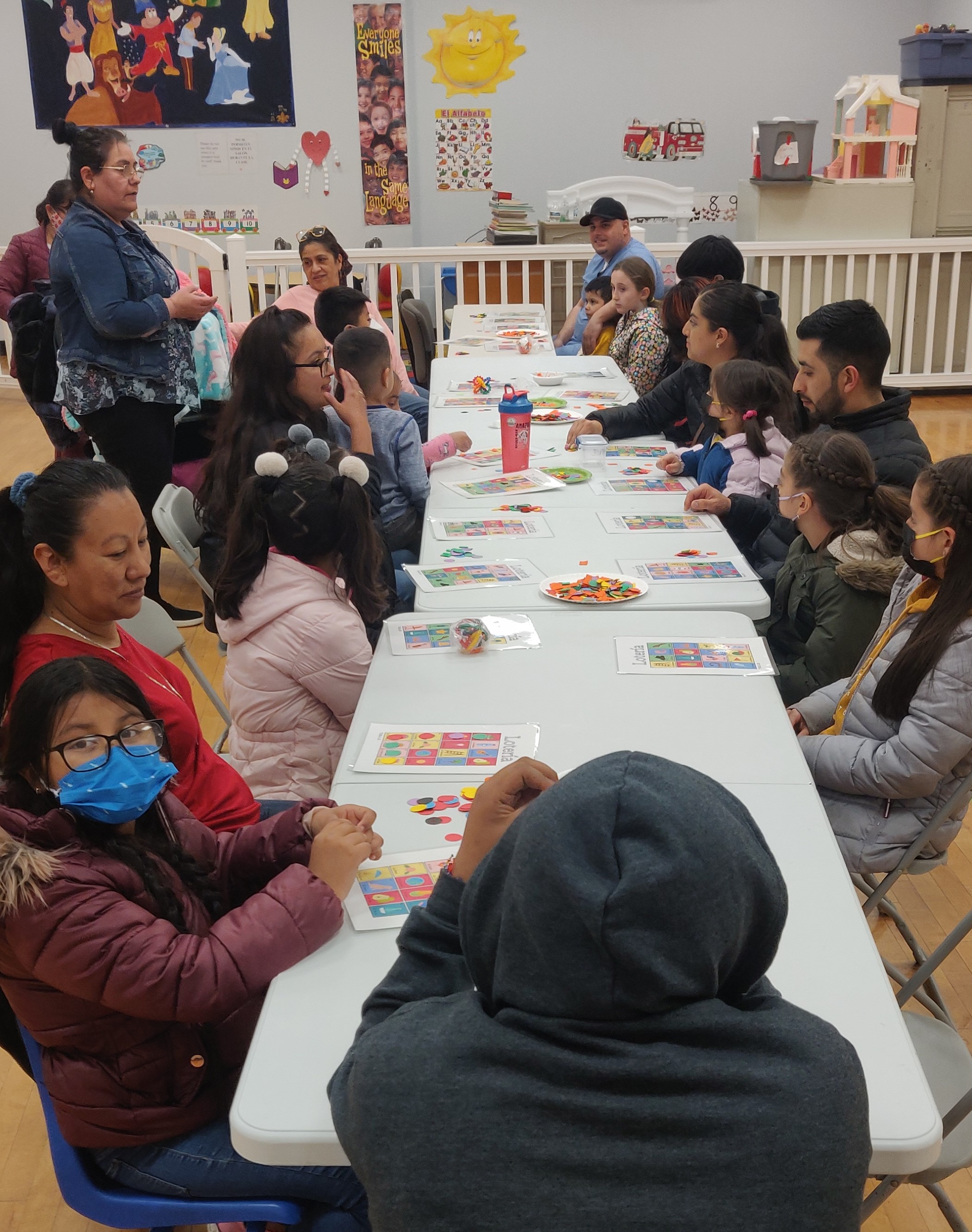 Group of people sitting down in a long table, waiting for their next Loteria game to start. 