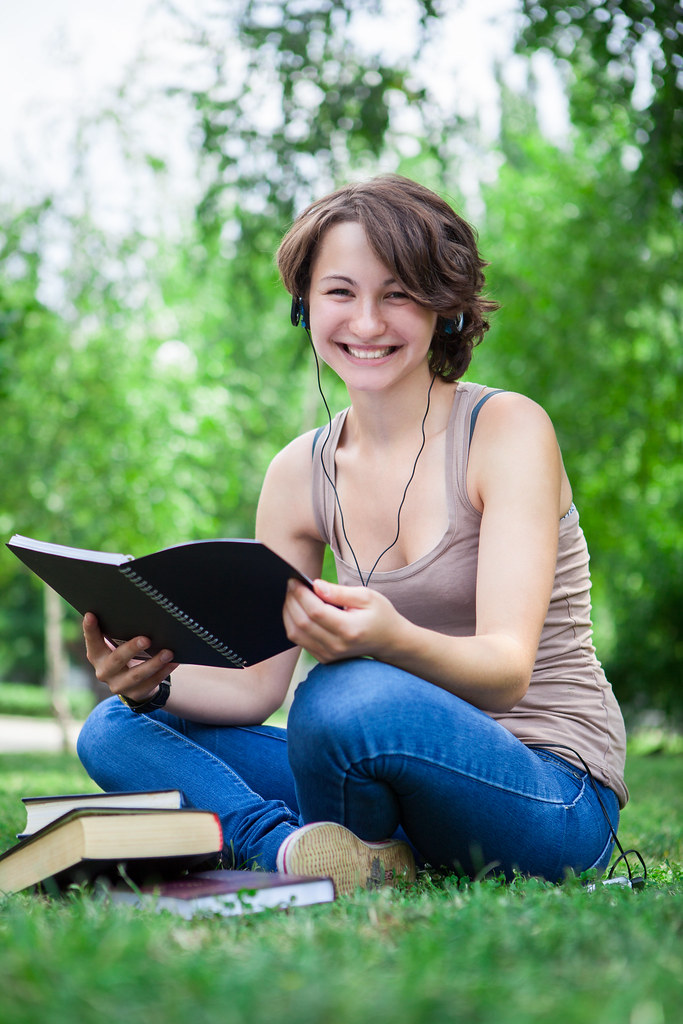 image of a young woman sitting outside holding a book.