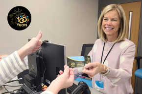 Staff handing member new 100 year library card