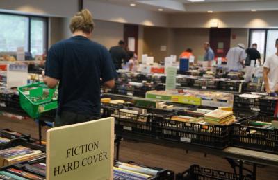 photo of friends sale with tables filled with books and people browsing