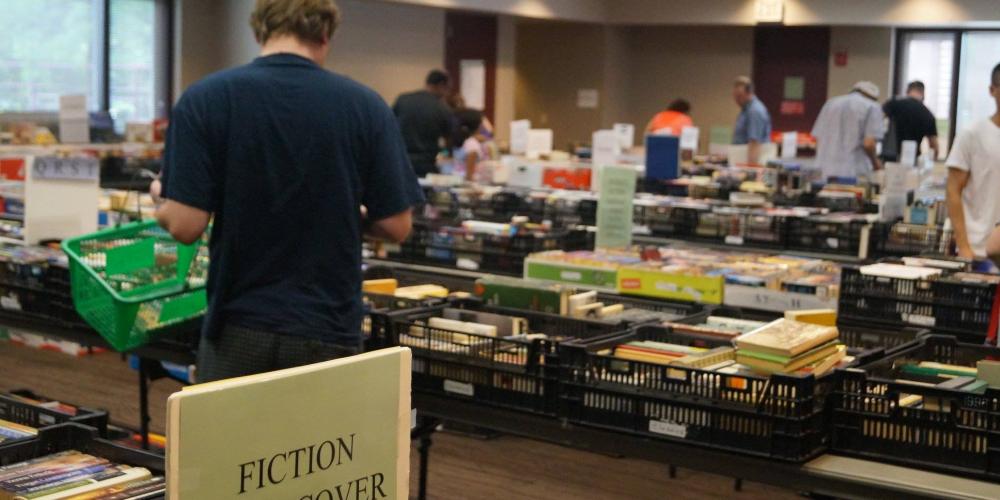 photo of friends sale with tables filled with books and people browsing