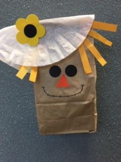 paper bag scarecrow with coffee filter hat, yellow straw hair, and sunflower