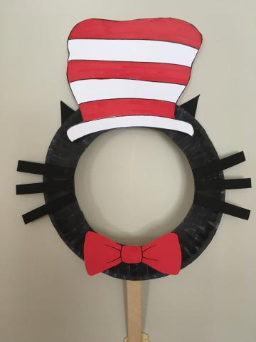 black face mask with red and white striped hat, red bow tie, black whiskers and ears