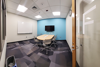 Study Room 1F showing a table with six rolling chair, a white board, and a digital display