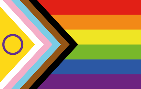 Image of the Intersex Pride Flag which includes a yellow triangle, purple open circle, white, pink, light blue, brown and black arrows and red, orange, yellow, green, blue and purple horizontal stripes.