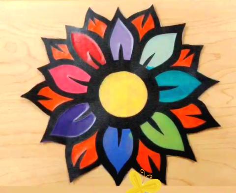 A black flower silhouette with different color pieces of tissue paper in the blank space to create a colorful suncatcher
