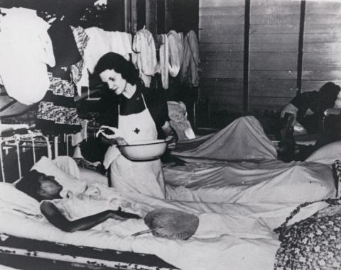 Photo of Nurse Peg Nash with a patient inside infirmary at the Los Banos prison camp.